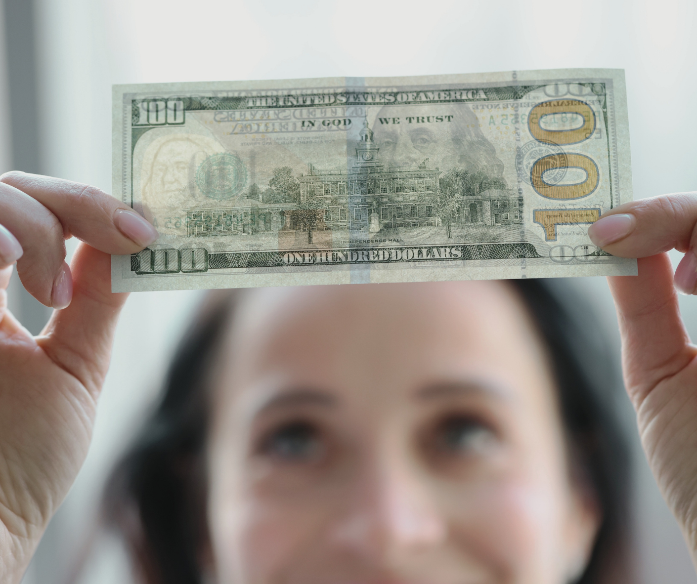 Woman holding up a shared $100 bill